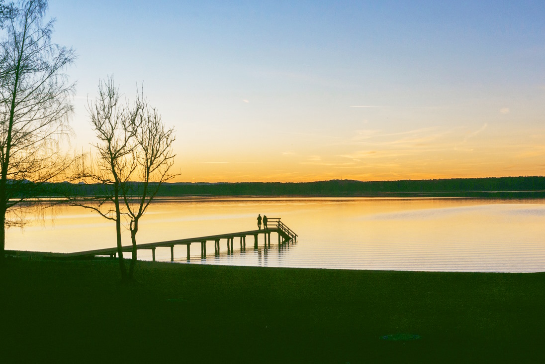 Ein Bild von einem Steg an einem See in den Abendstunden.